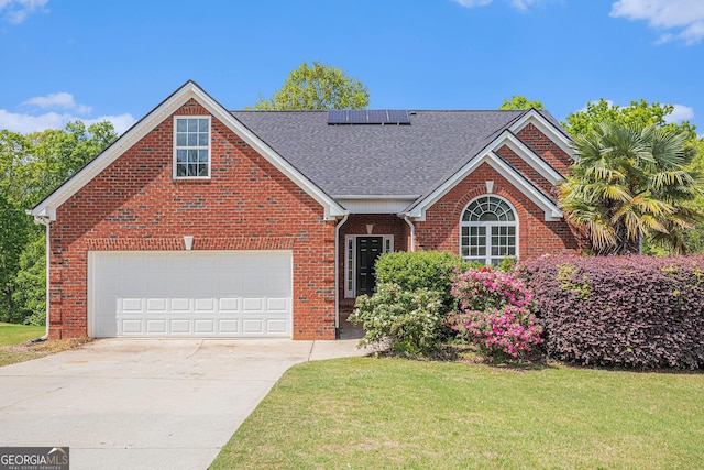 view of front of property featuring roof mounted solar panels, a shingled roof, driveway, and a front yard