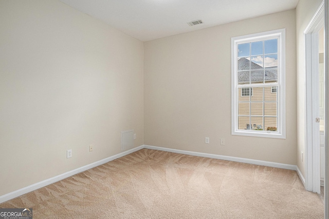 spare room with baseboards, visible vents, and light carpet