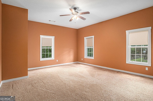 spare room featuring a wealth of natural light, carpet flooring, and ceiling fan