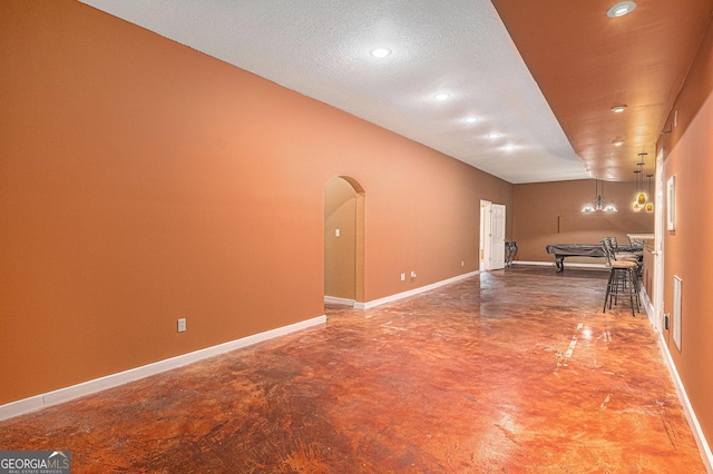 spare room featuring arched walkways, concrete flooring, recessed lighting, and baseboards