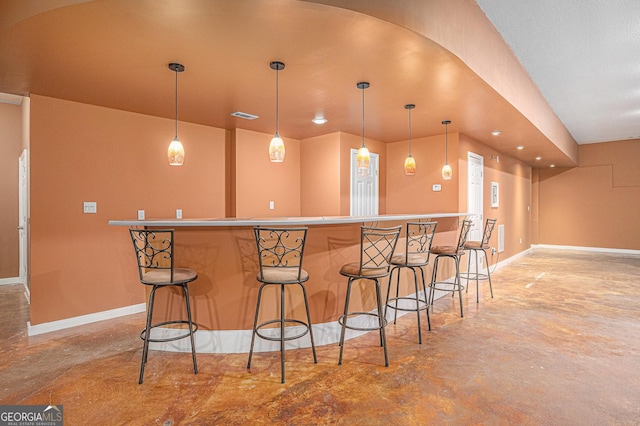 kitchen with a kitchen bar, finished concrete floors, and visible vents