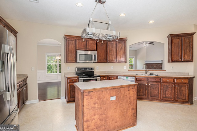 kitchen with stainless steel appliances, a center island, a sink, arched walkways, and light countertops