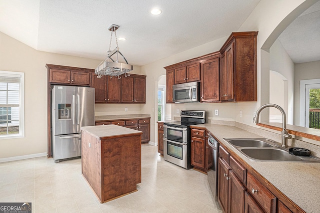 kitchen with arched walkways, appliances with stainless steel finishes, a sink, and a kitchen island