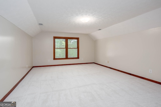 bonus room with vaulted ceiling, a textured ceiling, light colored carpet, baseboards, and visible vents