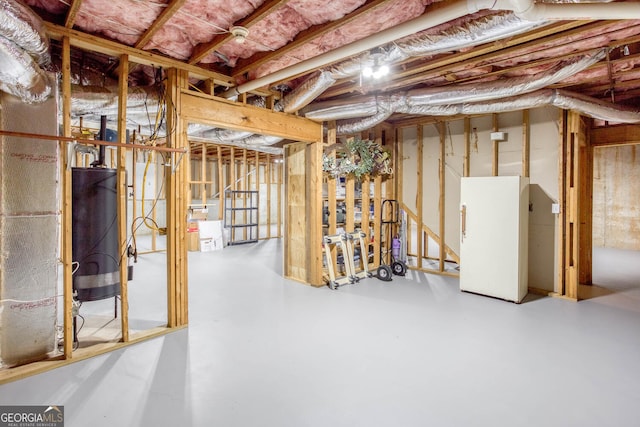 unfinished basement with water heater and freestanding refrigerator