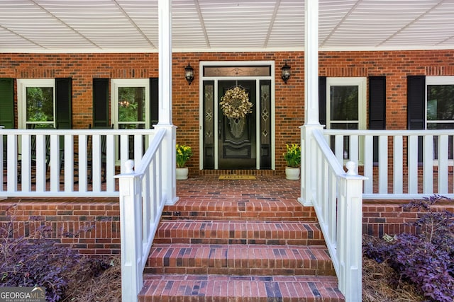 entrance to property featuring brick siding and a porch