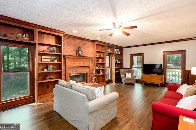 living area featuring dark wood finished floors, a textured ceiling, visible vents, a brick fireplace, and ceiling fan