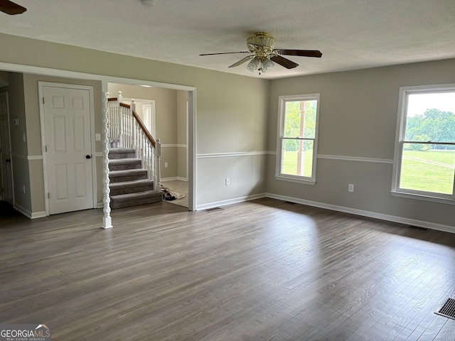 unfurnished living room featuring baseboards, stairs, ceiling fan, and wood finished floors