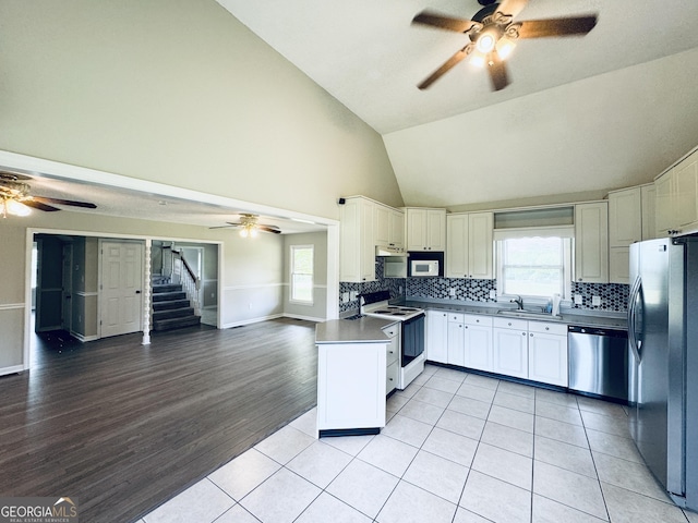 kitchen featuring a sink, high vaulted ceiling, stainless steel appliances, a ceiling fan, and open floor plan