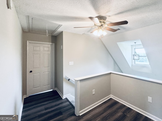 bonus room with a ceiling fan, attic access, dark wood-style flooring, a textured ceiling, and baseboards