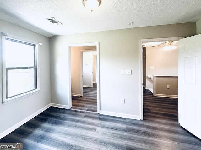 unfurnished bedroom with visible vents, a textured ceiling, baseboards, and wood finished floors