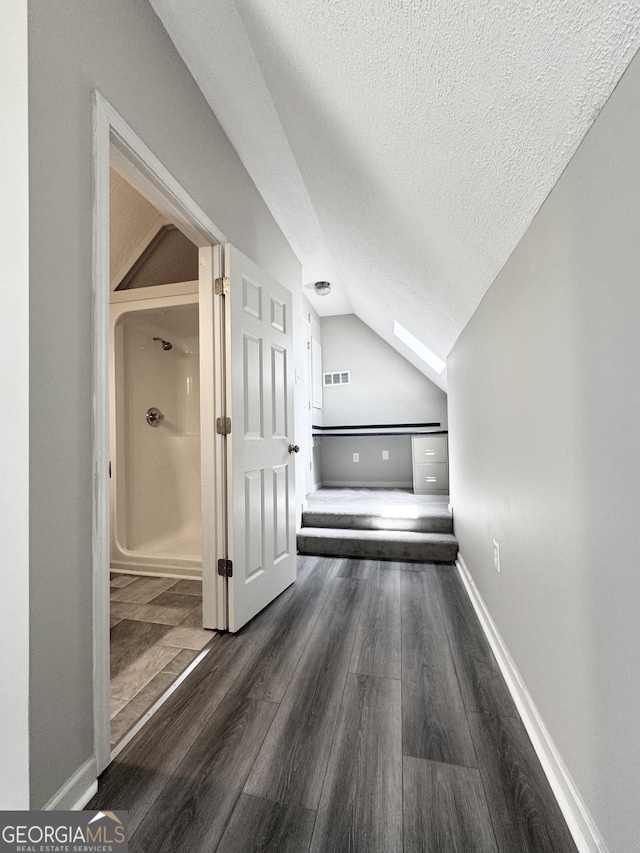bonus room with a textured ceiling, visible vents, wood finished floors, baseboards, and lofted ceiling with skylight