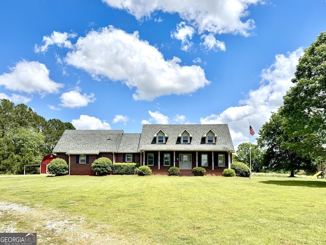 cape cod home with a garage, a shingled roof, brick siding, and a front yard