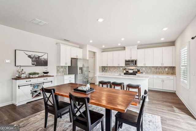 dining space with recessed lighting, wood finished floors, visible vents, and baseboards