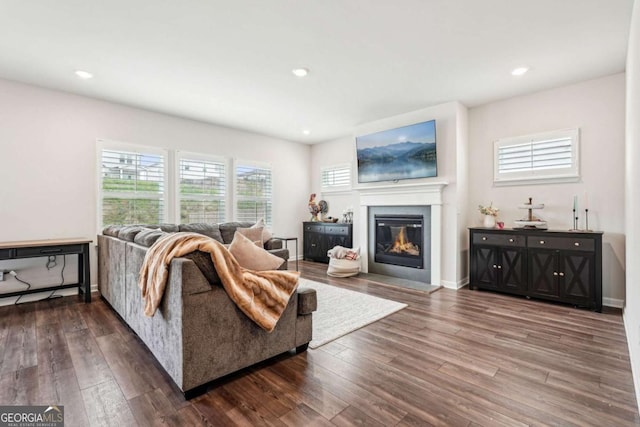 living area with baseboards, a glass covered fireplace, dark wood-type flooring, and recessed lighting