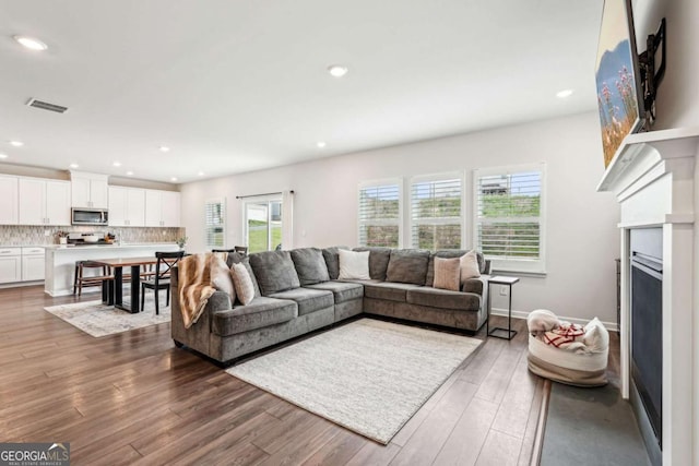 living area featuring recessed lighting, wood finished floors, visible vents, and a fireplace