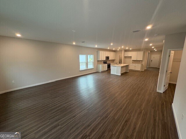 211 Park View Ln, Kingsland, GA 31548 - unfurnished living room featuring dark wood-type flooring, baseboards, recessed lighting, and a sink