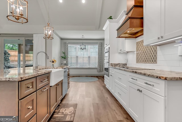 303 Wilsons Creek Bnd, Bonaire, GA 31005 - kitchen featuring a sink, light wood-style floors, a notable chandelier, custom exhaust hood, and appliances with stainless steel finishes