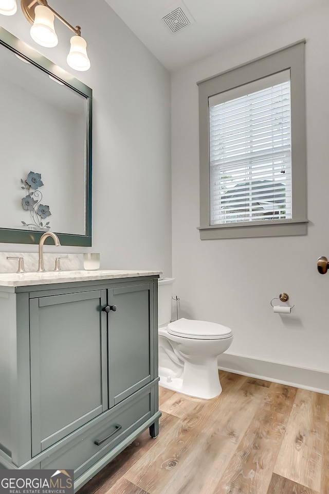 303 Wilsons Creek Bnd, Bonaire, GA 31005 - half bathroom featuring wood finished floors, toilet, vanity, baseboards, and visible vents