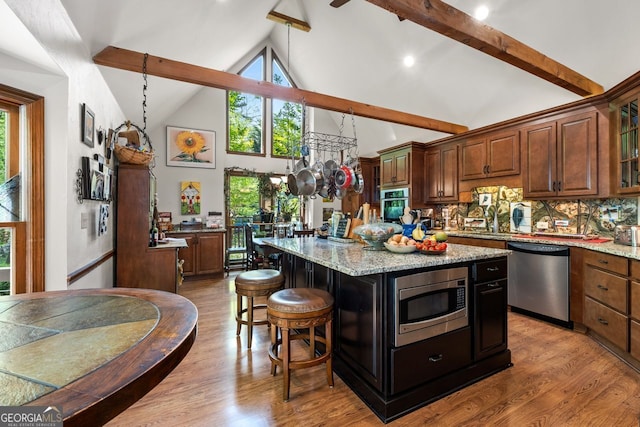 511 Oakdale Rd, Canton, GA 30114 - kitchen with wood finished floors, high vaulted ceiling, a breakfast bar, beam ceiling, and stainless steel appliances
