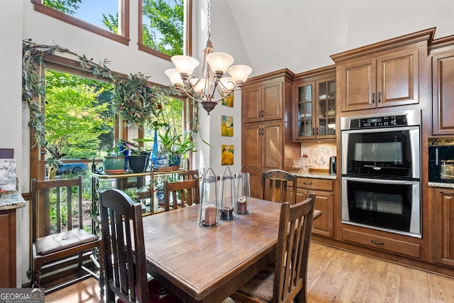 511 Oakdale Rd, Canton, GA 30114 - dining area featuring a chandelier, high vaulted ceiling, plenty of natural light, and light wood-style floors