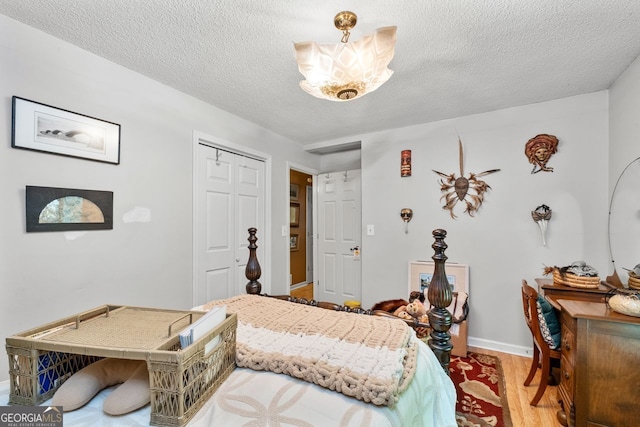 511 Oakdale Rd, Canton, GA 30114 - bedroom featuring baseboards, a closet, light wood-style flooring, and a textured ceiling