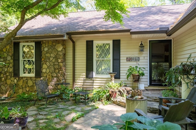 511 Oakdale Rd, Canton, GA 30114 - view of exterior entry with stone siding, a patio area, and roof with shingles