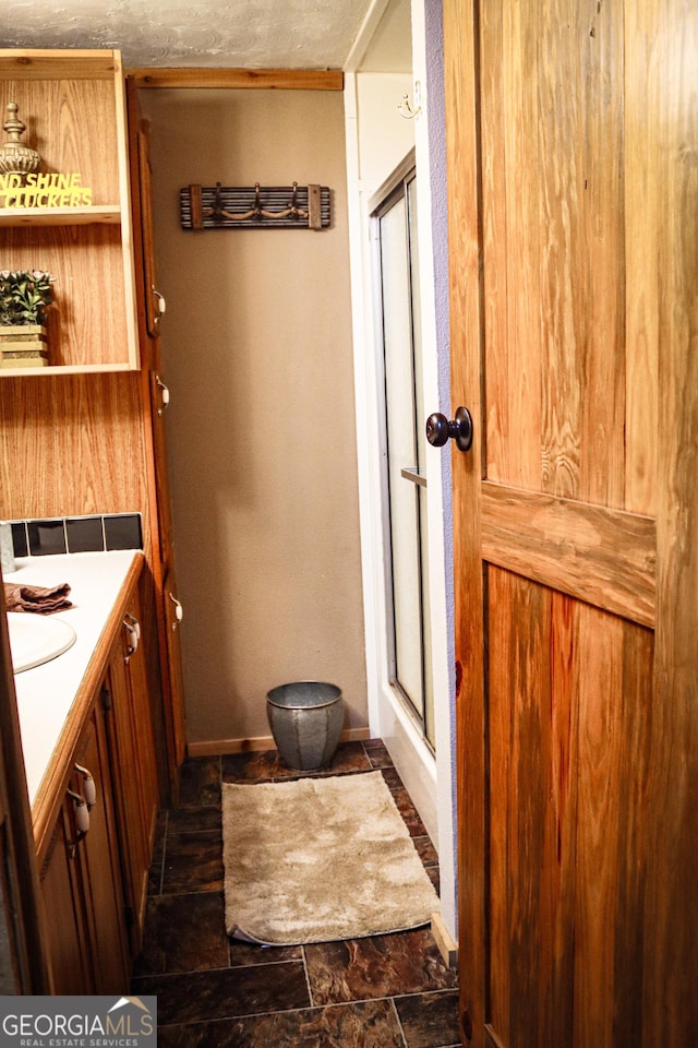 5524 Hooker Branch Rd, Millen, GA 30442 - full bathroom featuring a shower with shower door, vanity, baseboards, and stone finish flooring