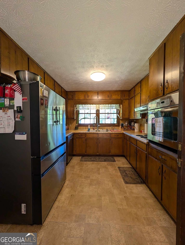 kitchen featuring light countertops, a sink, brown cabinets, and stainless steel appliances