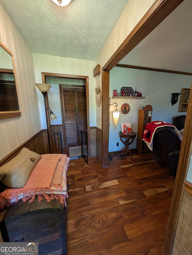 bedroom featuring a closet, a textured ceiling, wood finished floors, and wainscoting