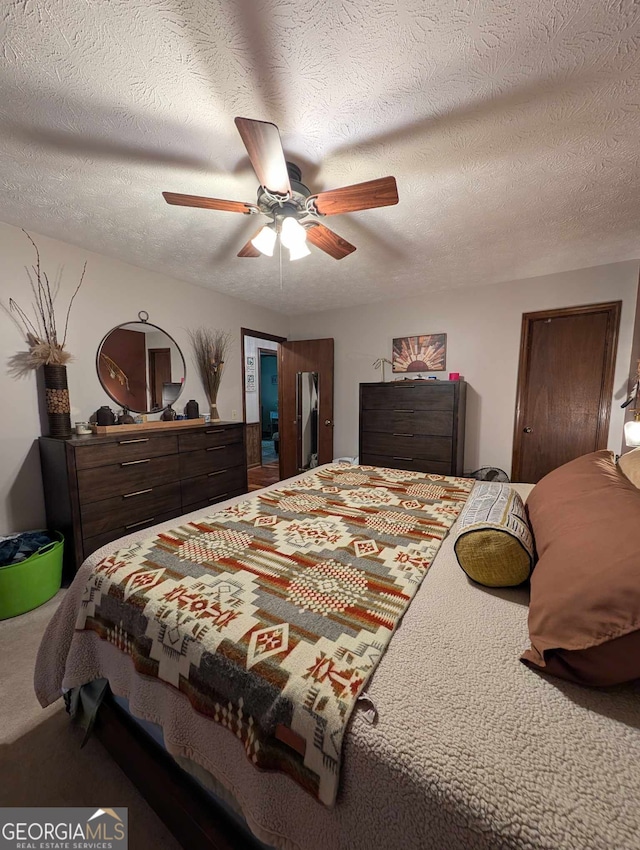 bedroom with ceiling fan, carpet, and a textured ceiling