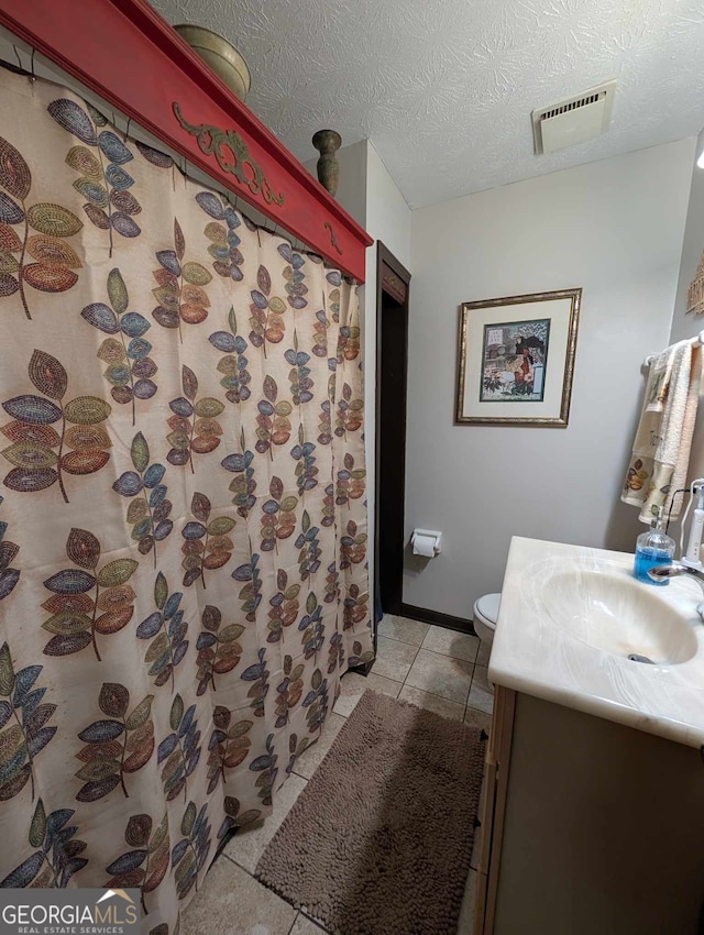 full bath with visible vents, vanity, toilet, a textured ceiling, and tile patterned floors