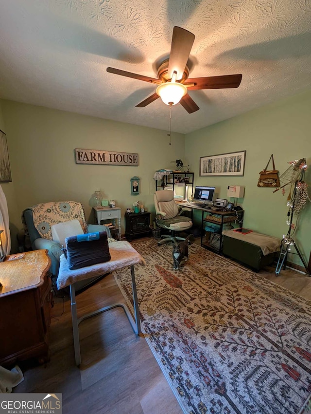 living area featuring a textured ceiling, a ceiling fan, and wood finished floors