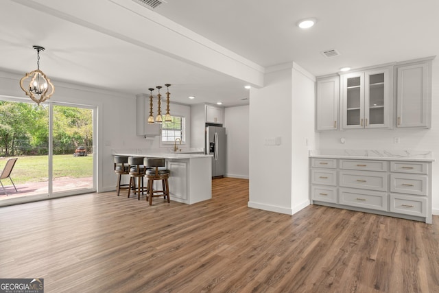 705 Oak Ln, Brunswick, GA 31523 - kitchen featuring stainless steel fridge with ice dispenser, a kitchen bar, a peninsula, light countertops, and glass insert cabinets