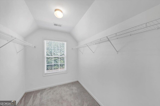walk in closet featuring carpet floors, lofted ceiling, and visible vents