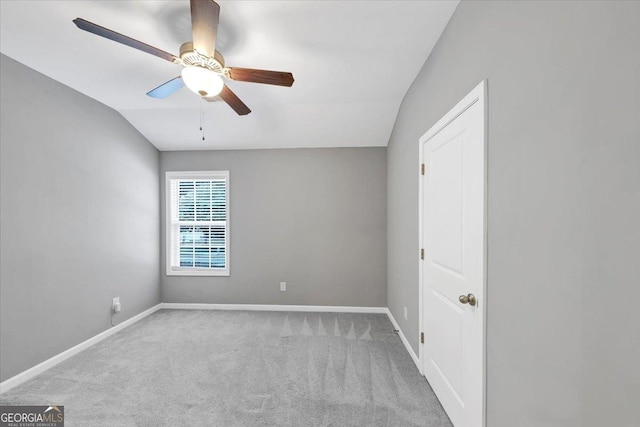carpeted empty room featuring vaulted ceiling, baseboards, and a ceiling fan