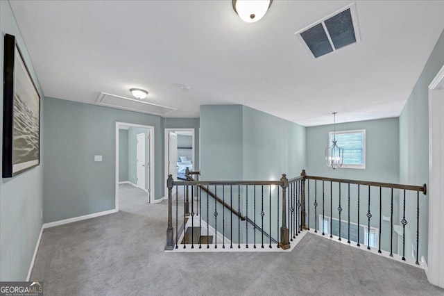 corridor with visible vents, an upstairs landing, baseboards, attic access, and carpet flooring