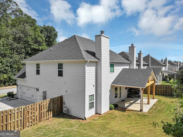 rear view of house featuring fence, a patio, a lawn, roof with shingles, and a garage