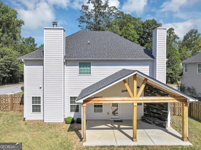 rear view of house featuring fence, a shingled roof, a chimney, and a yard