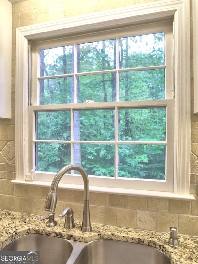 details with a sink, backsplash, and light stone countertops