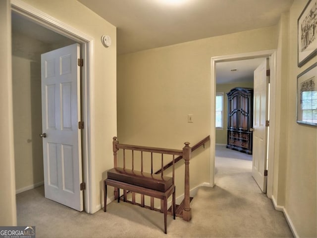 hall featuring baseboards, carpet flooring, and an upstairs landing