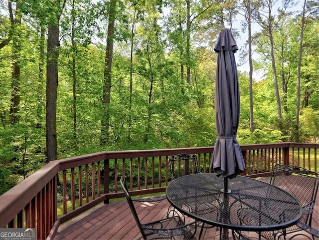 wooden terrace with a forest view and outdoor dining space