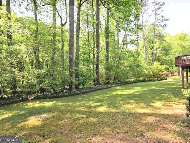 view of yard with a deck and a view of trees