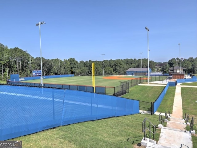 view of sport court with a yard, a view of trees, and fence