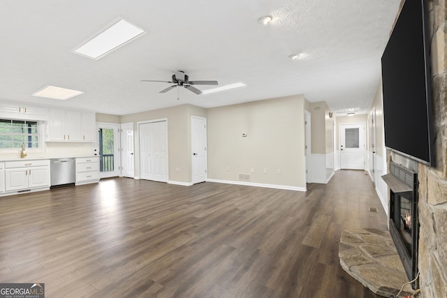 499 Old Deer Path Way, Cleveland, GA 30528 - unfurnished living room featuring a stone fireplace, dark wood-style flooring, baseboards, visible vents, and a ceiling fan