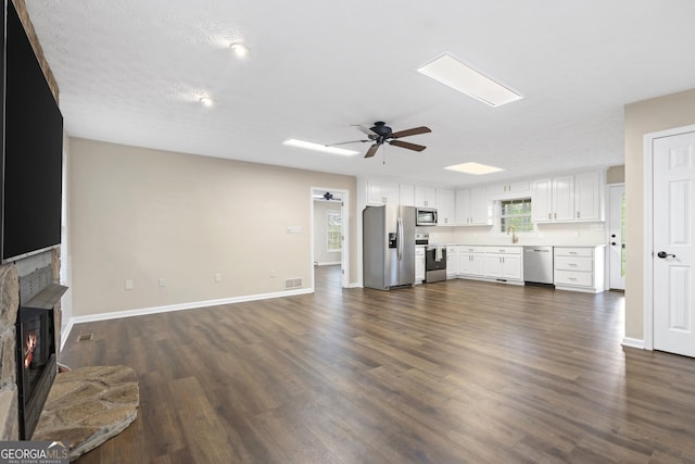 499 Old Deer Path Way, Cleveland, GA 30528 - unfurnished living room featuring baseboards, a warm lit fireplace, dark wood-style floors, visible vents, and a ceiling fan