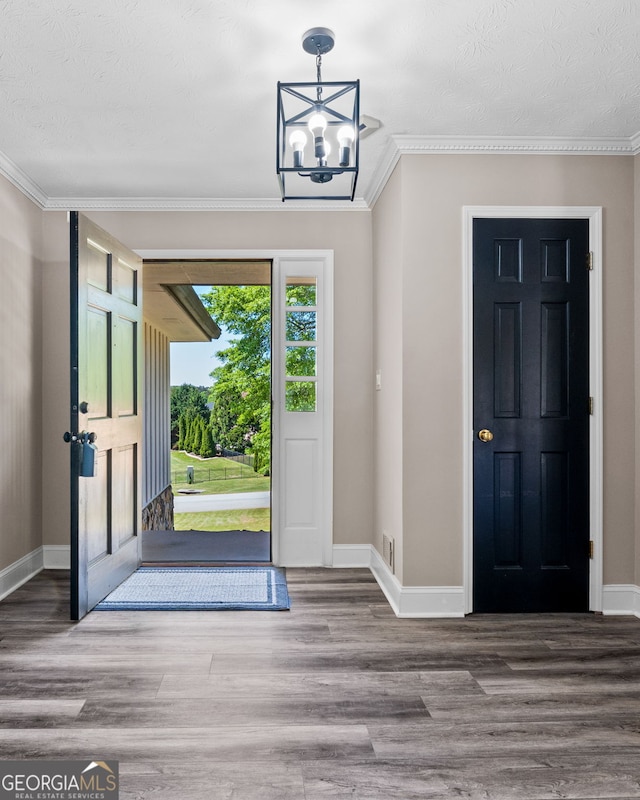 foyer featuring an inviting chandelier, crown molding, wood finished floors, and baseboards