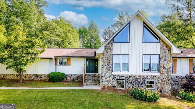 modern farmhouse style home with roof with shingles, stone siding, board and batten siding, and a front yard