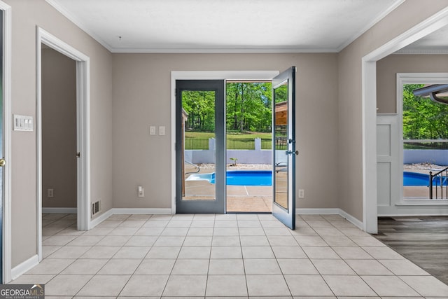 doorway to outside featuring a wealth of natural light, crown molding, baseboards, and visible vents