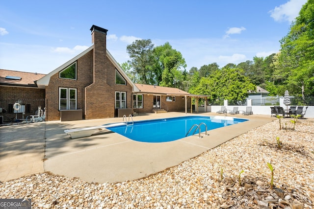 view of pool with a patio area, a fenced in pool, fence, and a diving board